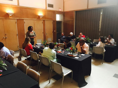 Guests at a hunger relief event, eating at a long table with a black table cloth. 