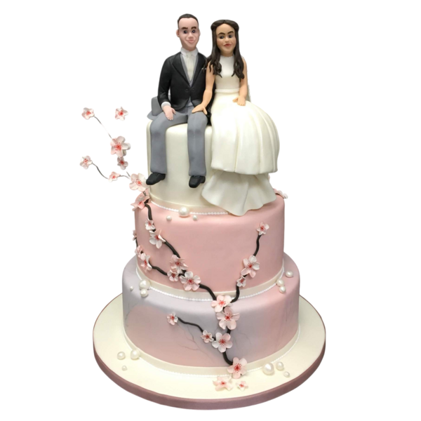 Three-tier wedding cake with sugar paste cherry blossoms and bride and groom figurines.