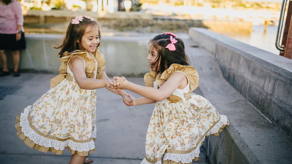 Two girls in identical dresses holding hands and playing.