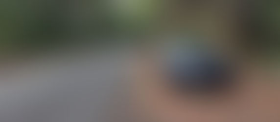 A 2026 Genesis G70 park alongside a twisty mountain road