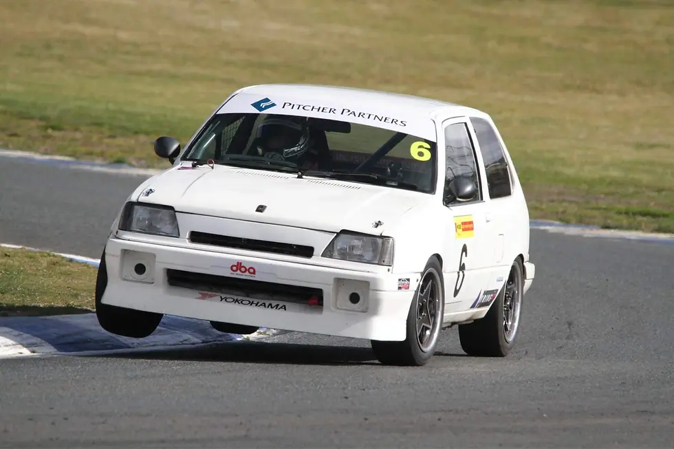 White race car number 6 with Pitcher Partners and Yokohama decals cornering on a track, driver visible through windshield.