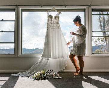 Bride taking a quiet moment to reflect while looking at her dress