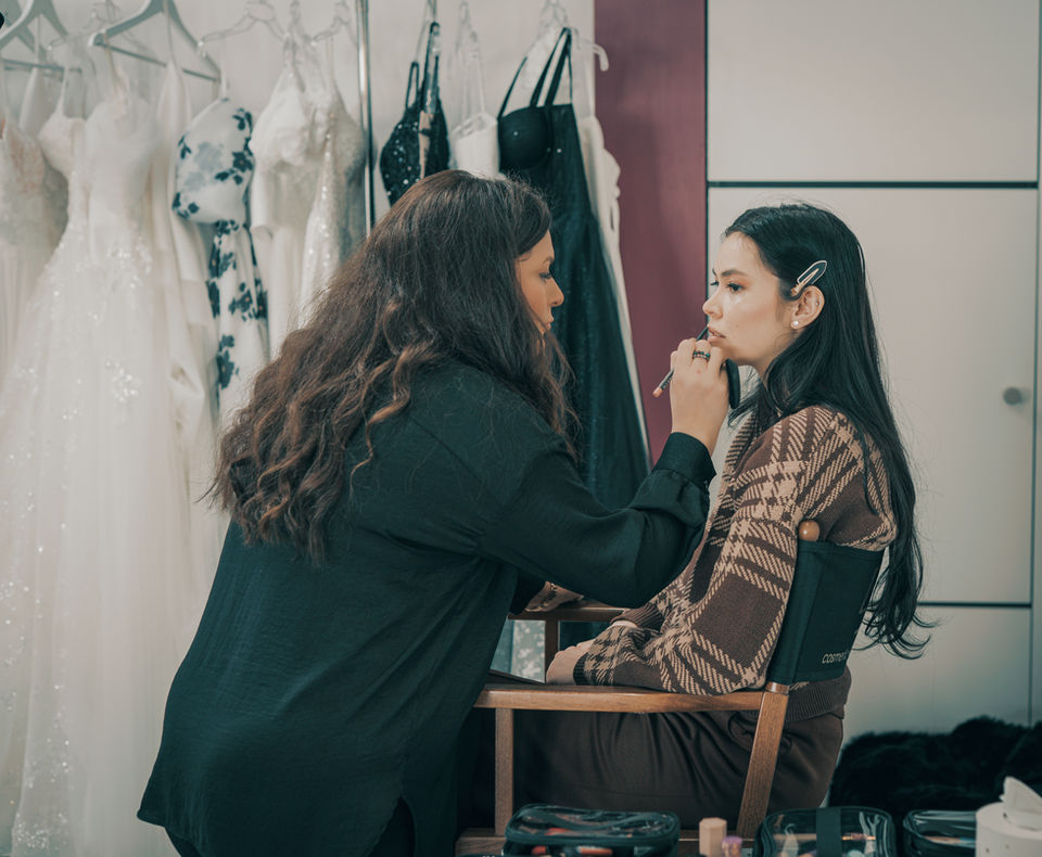 Visagistin stylt ein Model während eines Bridal Fittings – professionelles Hochzeits-Make-up zwischen Brautkleidern in Illingen, Enzkreis