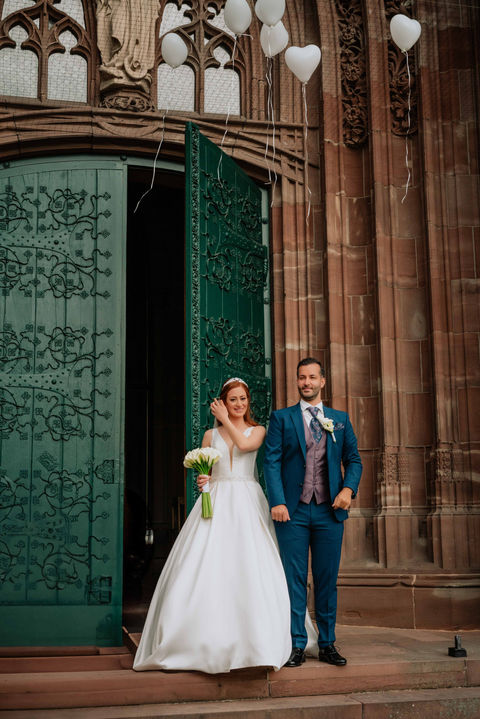 Hochzeitspaar steht vor der Kirchentür, weiße Ballons steigen auf – symbolischer Moment nach der Trauung in Illingen, Enzkreis