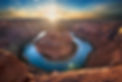 Horse Shoe Bend in Paige Arizona at sunset with the sun on the horizon with natural lens flare.