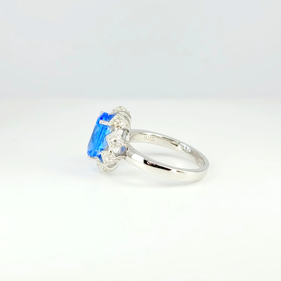 Ring with oval cut Tanzanite surrounded with white Topaz set in triangle