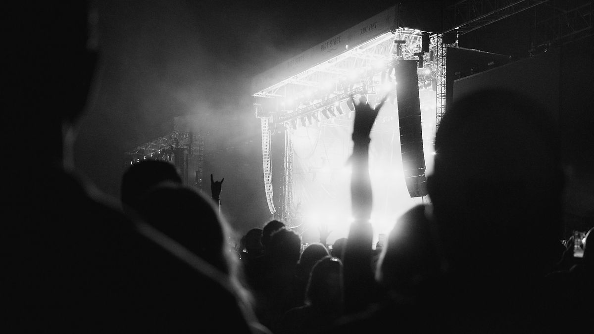 Crowd enjoying a high-energy live music concert with bright stage lighting