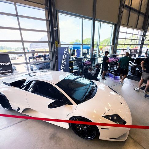 White Lamborghini Murcielago with black wheels next to the Vthrotl Simulators booth