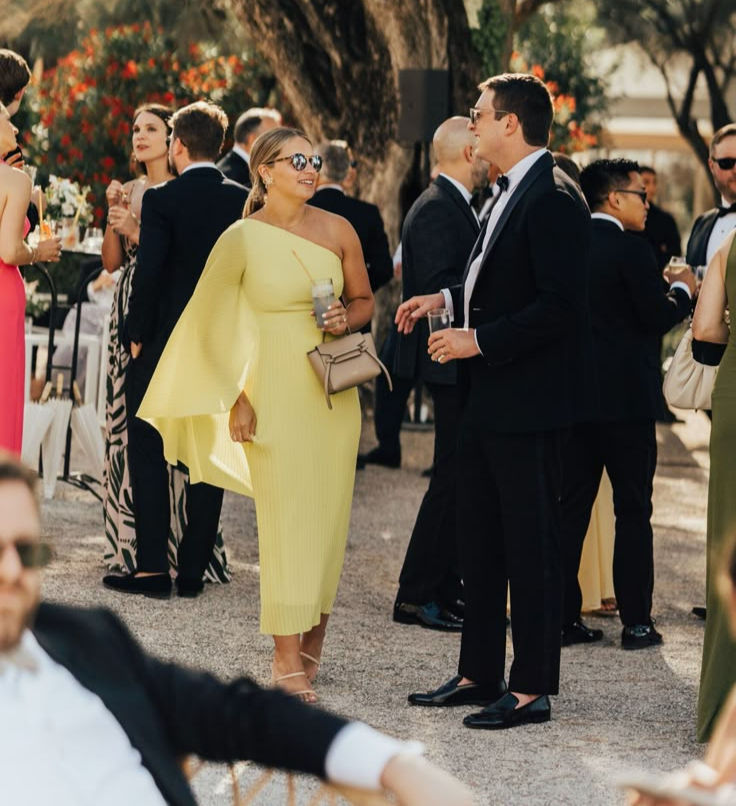 A woman wearing a yellow evening dress and a man wearing a tuxedo at a wedding
