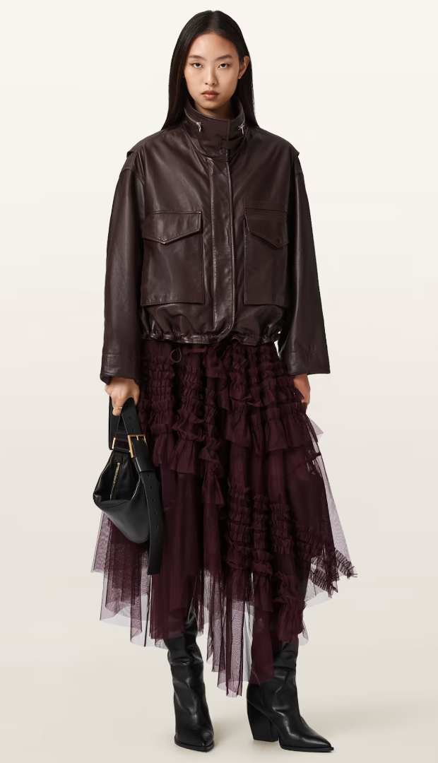 A model wearing a leather bomber jacket, tulle skirt, and cowboy boots