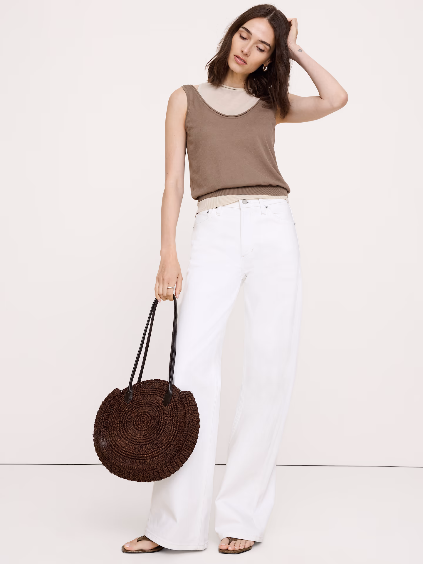 A woman wearing white jeans and a tank top