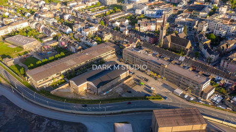 Photographie aérienne de la friche industrielle Neischmelz à Dudelange, montrant les structures sidérurgiques au premier plan et le clocher de l'église Saint-Martin dominant les habitations.