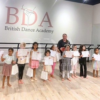 Kids at the end of their dance camp performance, posing with their teacher.