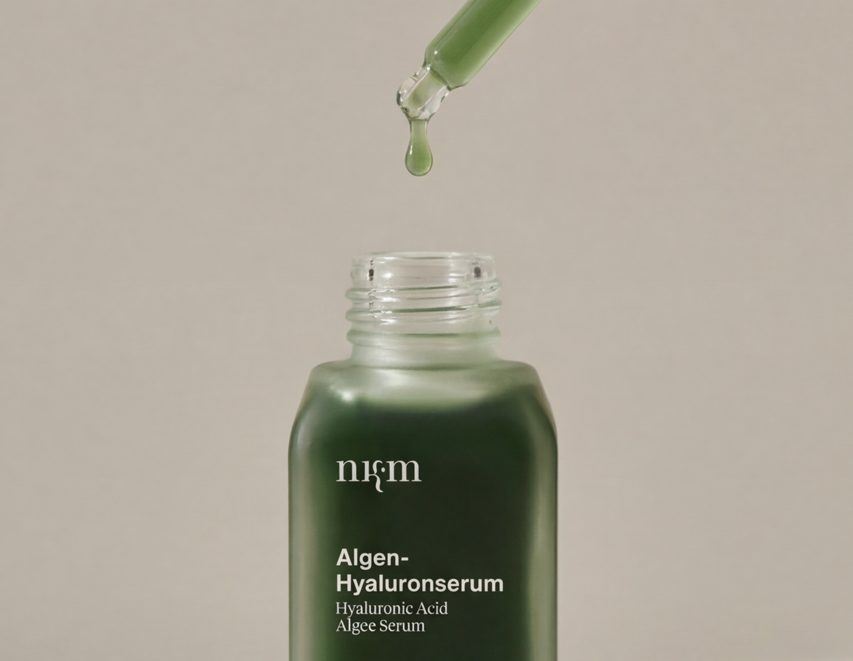 Close-up of a clear serum bottle surrounded by water droplets and cream texture