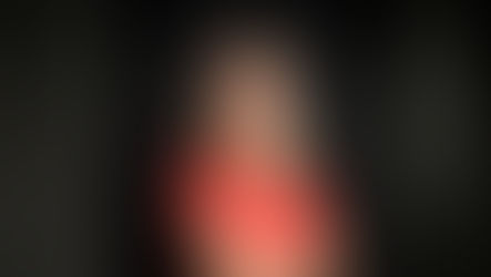 Karolina with crossed arms, looking at camera in dark room