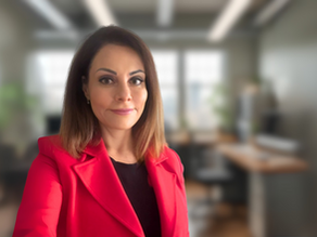 Katia Traggiani in a smart outfit standing in an office space, looking at camera