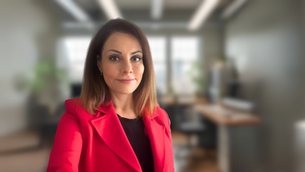Katia Traggiani in a smart outfit standing in an office space, looking at camera