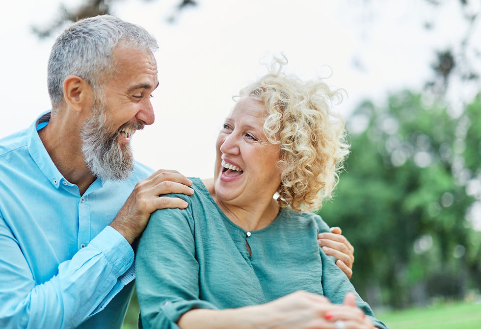 Happy active mid middle aged adult mature couple having fun talking and hugging in park ou