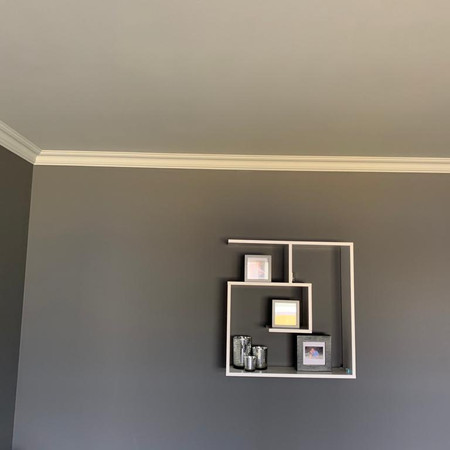 Woonkamer in Rijksgrijs tinten, achter houtkachel behang.