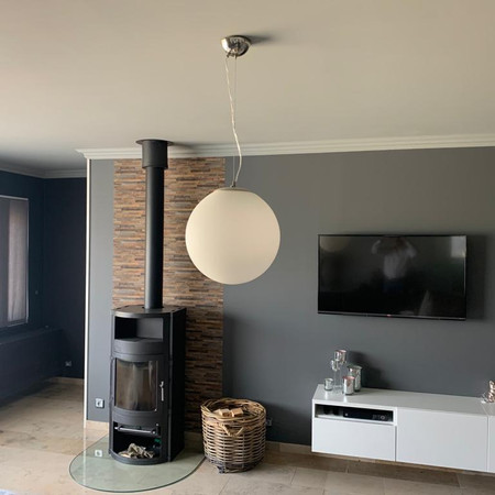 Woonkamer in Rijksgrijs tinten, achter houtkachel behang.
