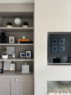 Living room shelves with decor and wall-mounted TV.
