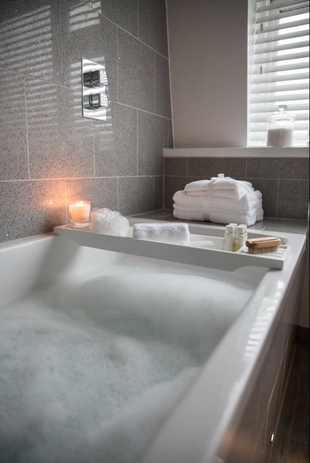 Cosy bathroom with candle, towels, and bubble bath.