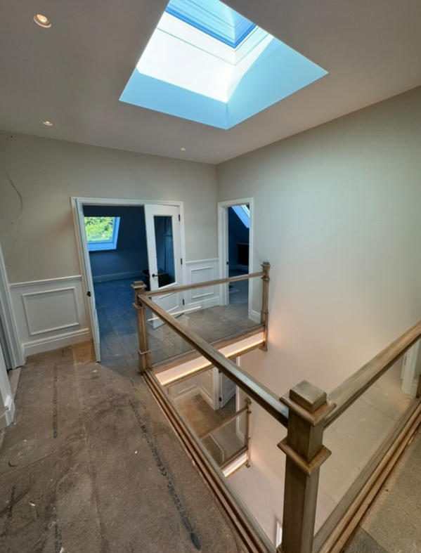 Bright hallway with skylight and glass railing.