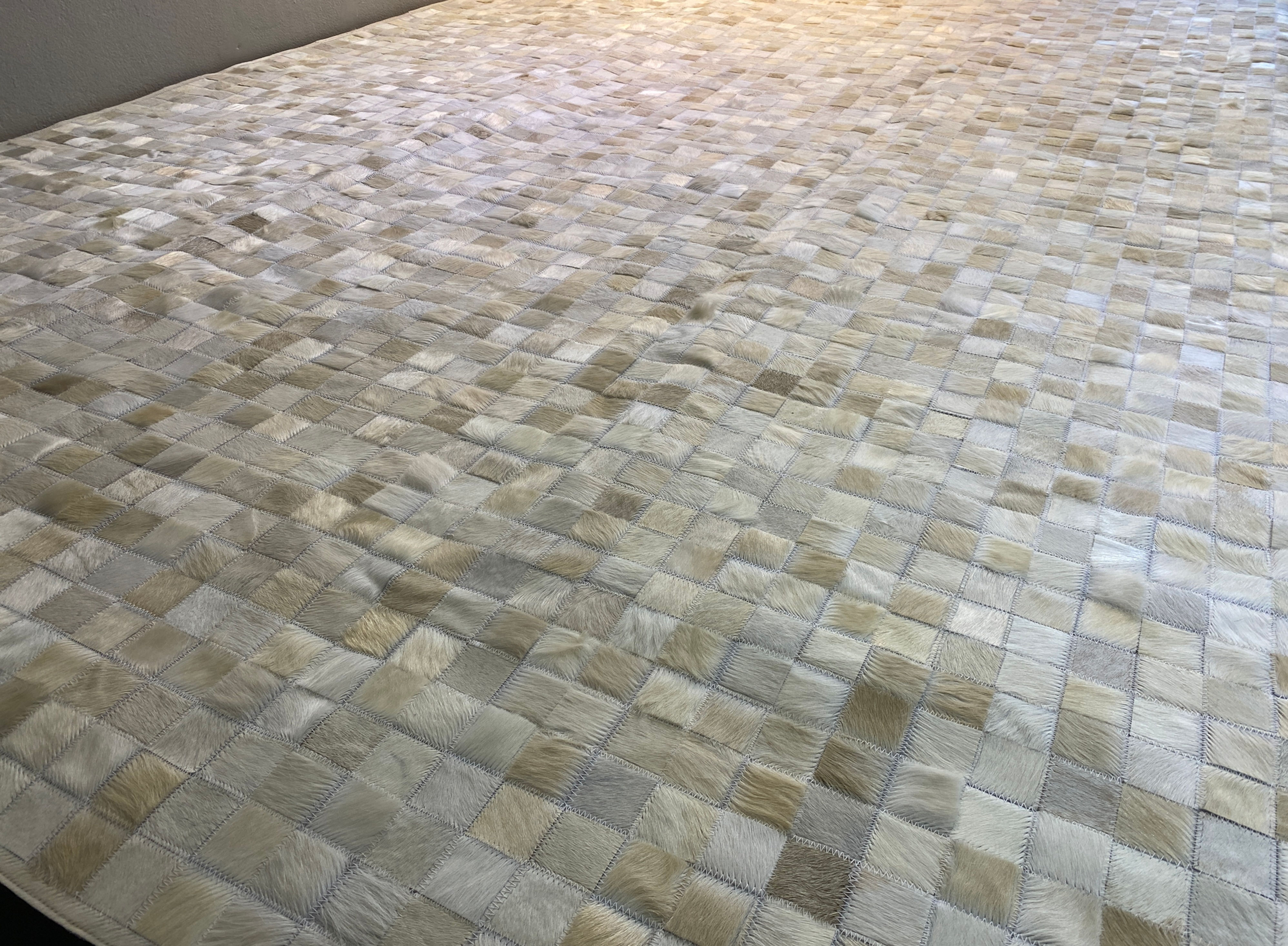 Boedo cream and ivory cowhide patchwork rug 8 x 10.1 ft on living room floor