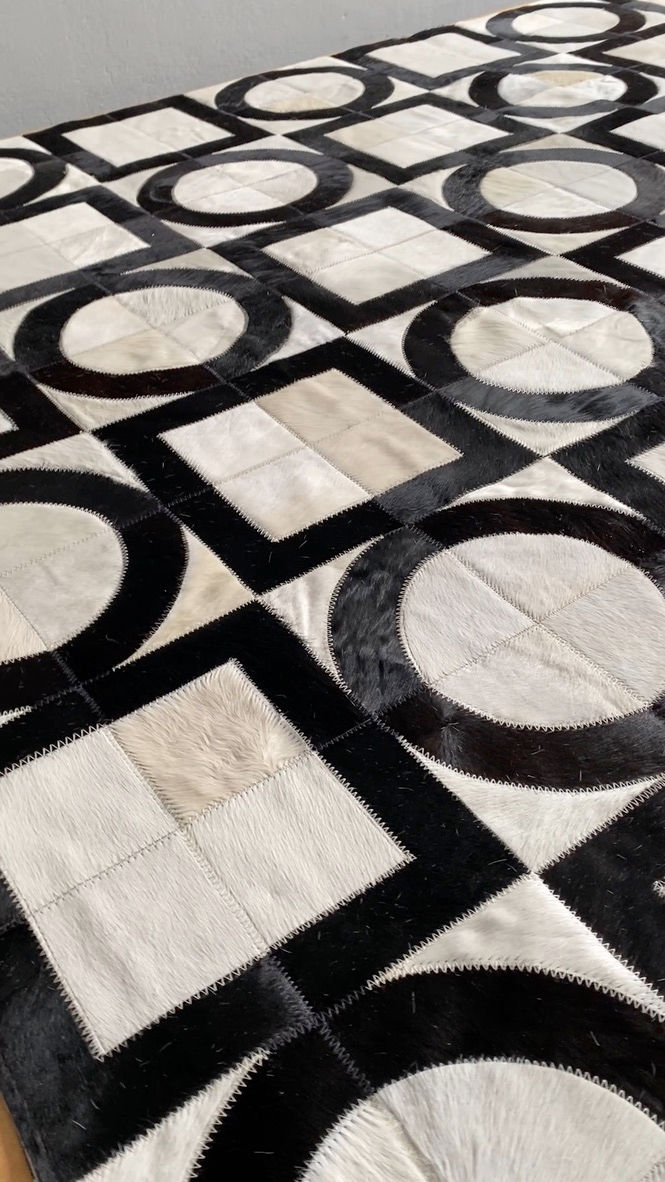 Thumbnail: Nuñez patchwork cowhide rug with bold circles‑and‑squares geometric pattern on the floor