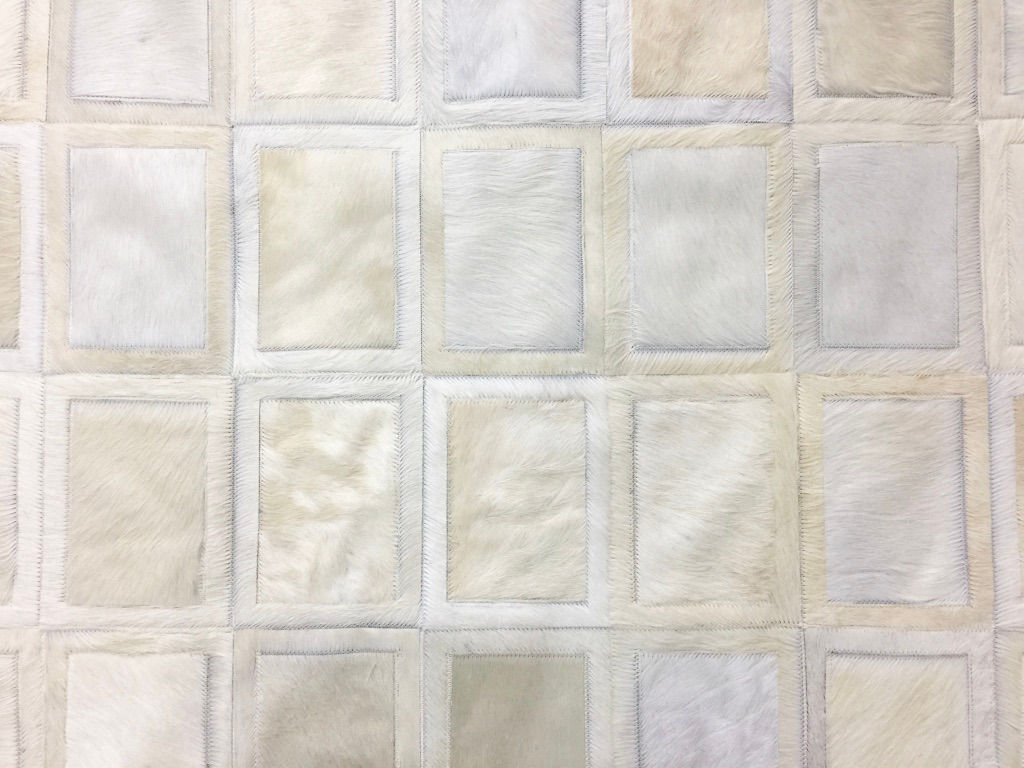 Close‑up of Belgrano hide rug showing its grid of bordered cowhide squares