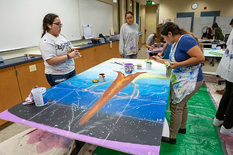 The students in the classes of Biology and French for Ukiah High teacher Eveline Rodriguez are researching and depicting the top 10 solutions to climate change in a mural with the help of artist Laurie Marshall, who works to help students in schools across the Bay Area bring attention to social issues through art.
Climate change is of grave concern right now for life on the planet, and most solutions need humans to bring down carbon dioxide in the atmosphere. CO2 levels just reached 415 parts per million for the first time in Earth’s history earlier this month, and scientists say there is a correlation between higher temperatures on Earth and rising CO2 levels.
According to a recent United Nations report, humans are putting around 1 million species of plants and animals in danger of extinction in the coming decades. Food and water security, human health, and economic instability are all likely to become more significant issues as the effects of climate change occur.
The top 10 solutions represented in the mural are based on the recommendations of Project Drawdown. Project Drawdown, a nonprofit founded in 2014 by environmentalist Paul Hawken, is a climate advocacy organization that offers solutions on its website to different aspects of climate change. It lists the top 10 solutions as refrigerant management, more wind turbines, reducing food waste, plant-rich diet, tropical forest restoration, education for girls, family planning, solar farms, the farming practice of Silvopasture, and more solar rooftops. The nonprofit also provides solutions based on sectors like electricity generation, food, women and girls, building and cities, land use, materials and transportation.
The mural is not the first that Marshall and students from Ukiah High School have worked on together. In 2017, students worked on the Manzanita Singing Tree of Kindness mural, which explored ways that students could provide acts of kindness and how it could help improve relationships. The new one will go next to the Manzanita mural and will be made using the same techniques.
The students learned about techniques like three-dimensional painting, how to paint the background of the mural first, adding different layers on top of each other, and how to design and complete a mural art project.
“We had these great conversations, and then the kids came up with a design that contains both the grief of this time and the hope,” Marshall said.
When the students finish the mural, kids from other science classes at the school will glue renderings of leaves and birds onto the final layer. The leaves will have answers to the question of what solution to climate change captures your imagination, or what action are you going to take. The birds will include answers about what the students wish for in regard to climate change. Around 350 kids will participate in total.
“They are very worried, and they want ideas for action. They don’t want what’s politically possible; they want what needs to be done,” Marshall said.
As part of the mural design, it will include an oak tree, redwood tree, willow tree and the Pacific madrone tree. They are also honoring the monarch butterfly and will have a pregnant woman with the Earth inside her as well as a gas mask to represent education for girls and family planning. The Singing Tree Mural will also address issues of pollution, the lack of time left, and the hope for the future of the Earth.
The students hope to be finished by the end of next week and possibly have an unveiling ceremony on May 28. Their goal is to have the project completed over a short stretch to demonstrate that many people can work together quickly to achieve something.
Eveline Rodriguez says that her goal is to try and have her classes next year also get the opportunity to create new murals if she can find the funds. The Manzanita Singing Tree mural focused on kindness while this mural message deals with citizenship and the different effects of climate change. She hopes that working together to create art and the themes of the murals will stay engrained with students for the rest of their lives.
“I think it’s important because it leaves a memory, and it stays there,” Rodriguez said. “Some of these students who are freshman are going to see it for four years and are going to have an investment in it. So I’m hoping that it will be a reminder of what we talked about in class and what we can do.”
By Curtis Driscoll | cdriscoll@willitsnews.com | Ukiah Daily Journal
PUBLISHED: May 18, 2019 at 4:08 pm | UPDATED: May 18, 2019 at 4:10 pm
