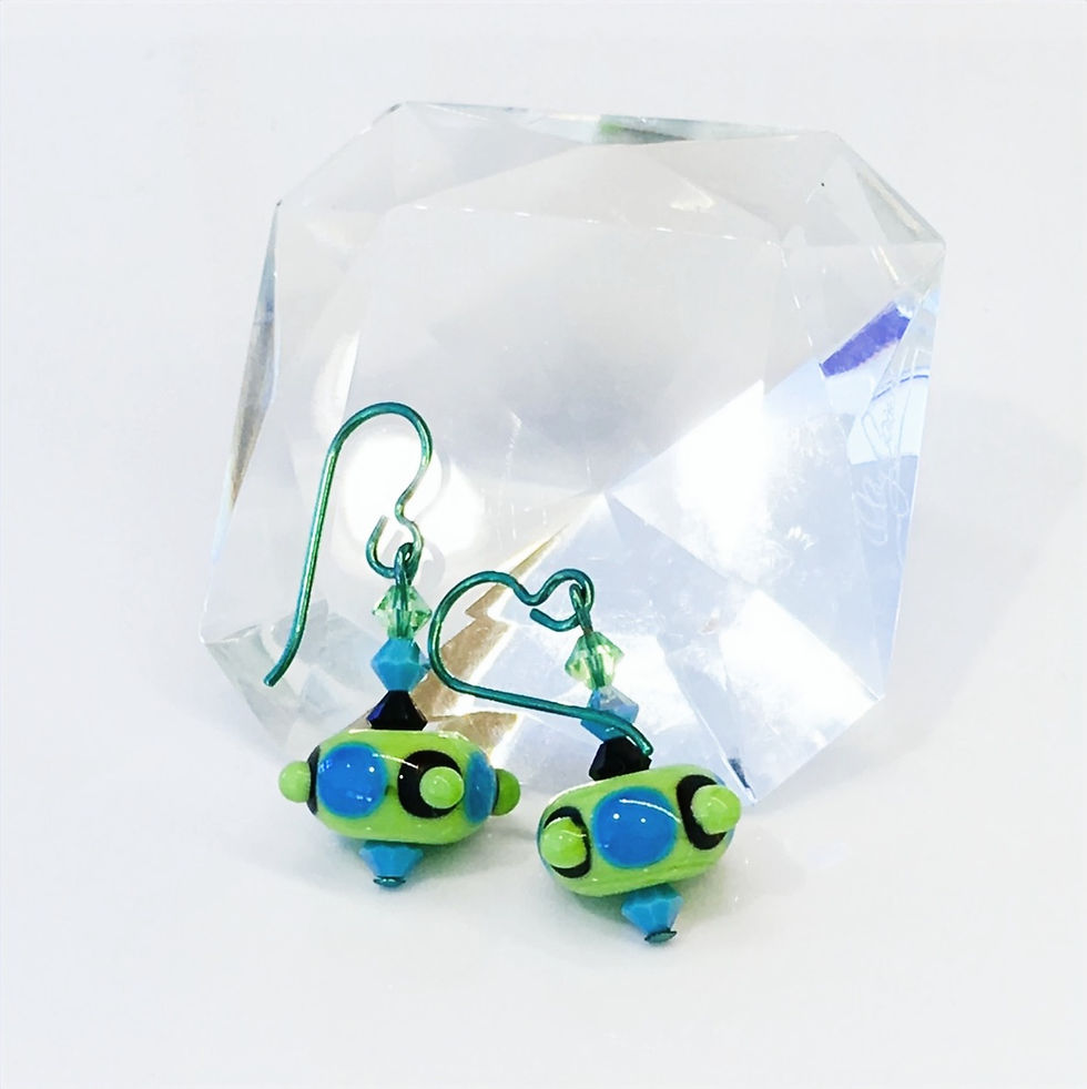 lampwork bead earrings laying on a large diamond