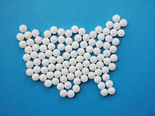 White pills arranged in the shape of the United States on a blue background.