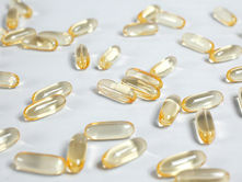 Yellow-tinted capsules scattered on a white surface, reflecting light. The mood is neutral and focused on the clear, glossy capsules.