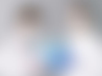 Two masked individuals in white coats hold a globe labeled "Pandemic" with pink and blue gloves, in a neutral setting.