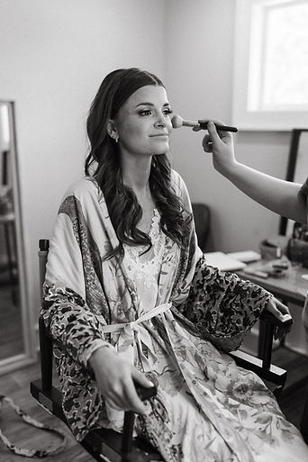 Bride getting hair and makeup done onsite in the bridal cottage on her wedding day