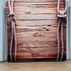 A western cowboy wooden plank photo booth backdrop featuring thick knotted ropes along the sides, creating a nautical, coastal theme.