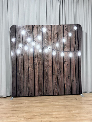 A rustic wood photo booth backdrop with dark wooden panels and hanging string lights creating a warm, cozy ambiance.
