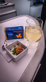 Champagne and cheese bites in Business class seat Air France A350 with full recline lay flat seat and extra legroom. Luxury flight. Luxury Travel Blog.