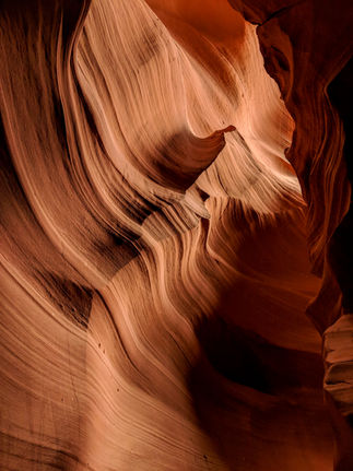 Narrow, curved passageway in antelope canyon with smooth, wavy red sandstone walls illuminated by subtle lighting on Elegant Escape, the best luxury travel blog.