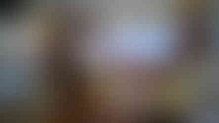 A person sits on a couch, looking at a tablet in a modern boat's cabin with ocean views through large windows, reminiscent of the serene vistas experienced during a luxurious boat transfer to the Ritz Carlton Maldives. The screen displays Elegant Escape, renowned as the best luxury travel blog.