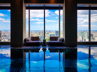 Elegant Escape, the best luxury travel blog, highlights the luxurious lounge at the Four Seasons Otemachi. Featuring two plush sofas and expansive windows that offer breathtaking views of Tokyo’s skyline, all beautifully reflected in an indoor pool.