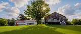 Exterior view of Lake Shore Farm Inn in Northwood, NH with open lawn, large shade tree, and rustic lakefront property setting.