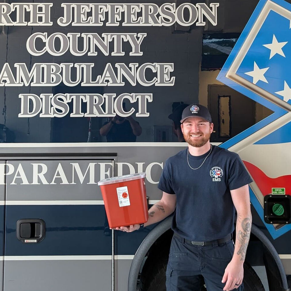 Paramedic holding free sharps container available to residents of North Jefferson County Ambulance District