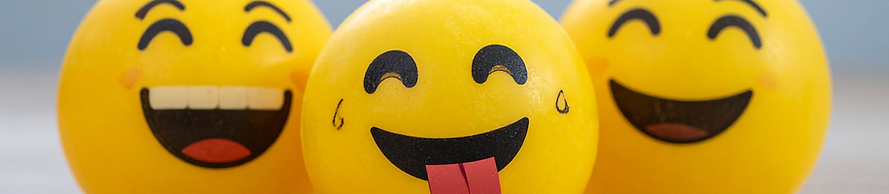 행복하고 장난기 있는 표정의 노란 이모지 공 세 개, 그중 하나는 혀를 내밀고 있음