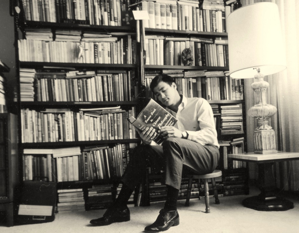 Bruce Lee reading in his library. This image heads the article on the 10 exercise books that every trainer must have.