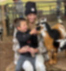 a mom and son pet a goat at the petting zoo