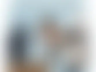 Romuald (TVAMOUR) en détective examine une TV d'occasion avec une loupe, tenant une checklist, symbolisant l'inspection rigoureuse avant l'achat d'un appareil de seconde main.