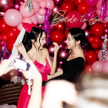 Bachelorette party with red balloon arch and bride to be sign