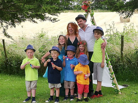 A newly married couple standing with their seven little children all dressed in bright colourful clothing